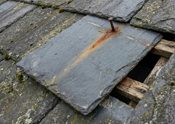 Drone image showing extreme close-up detail of a slate tile with rusted nail causing it to slip